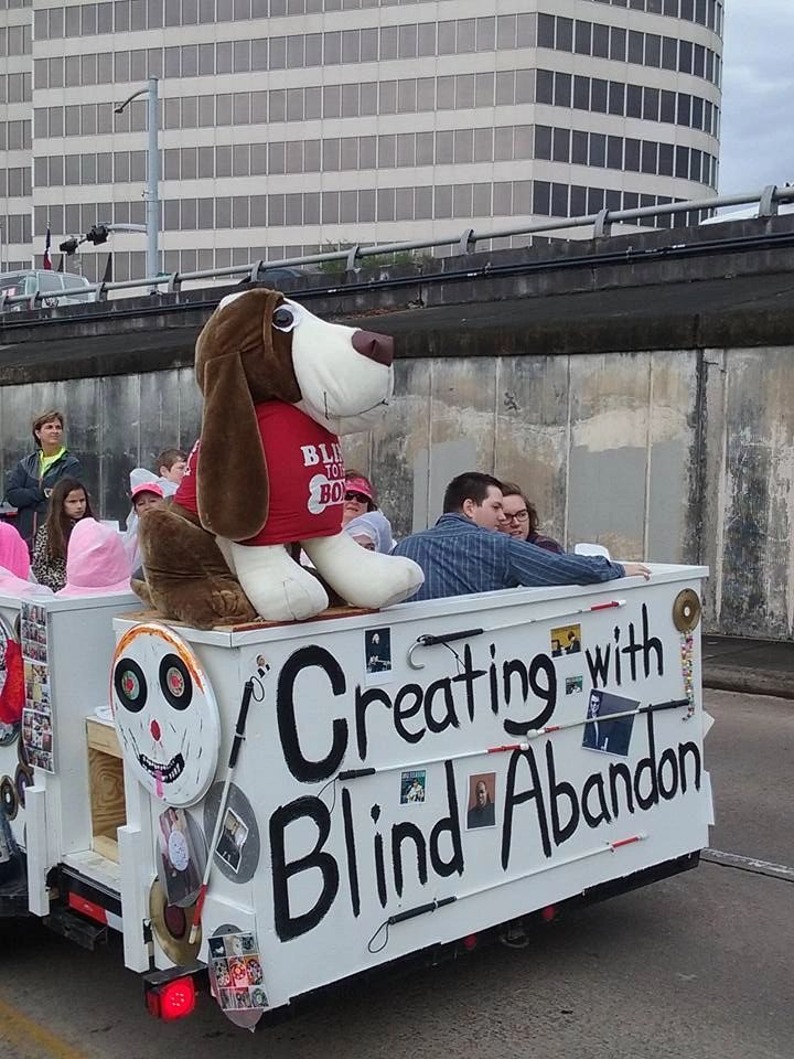 The float parked with the Houston skyline behind it, the stuffed hound mascot seated at the front wearing a Blind to the Bone shirt.