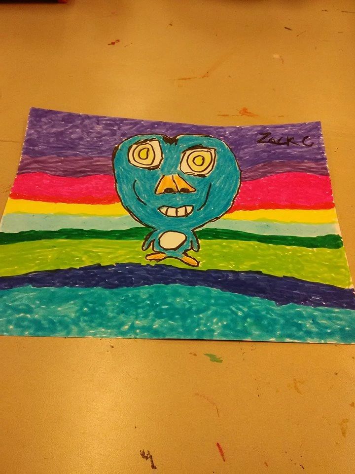A marker drawing of a smiling blue creature standing against horizontal bands of purple, pink, yellow, green and blue, signed Zack G.