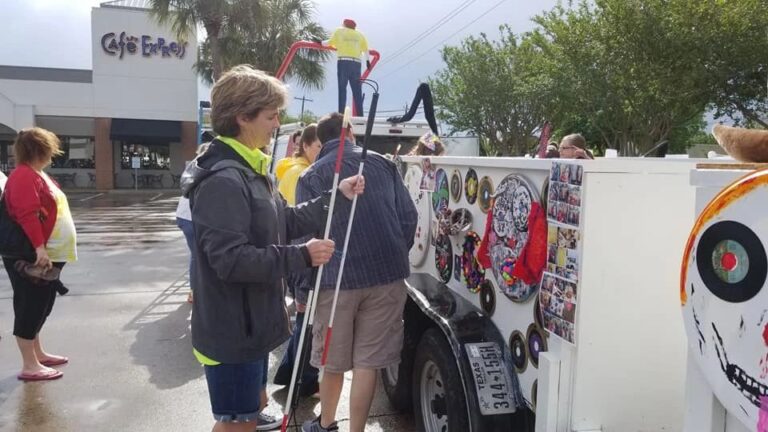 Two people sit close together on the float, one resting an arm around the other, both wearing Creating With Blind Abandon shirts.