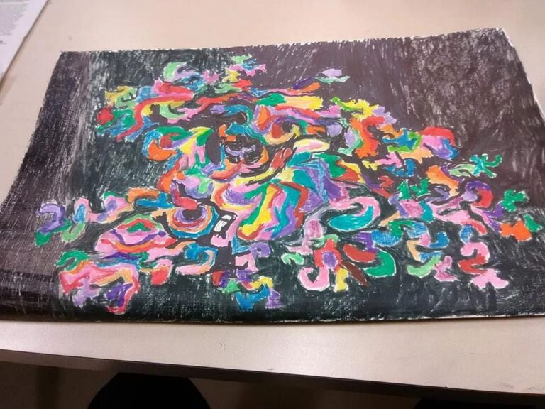 A marker drawing of swirling abstract shapes in red, orange, yellow, green, blue and pink against a dark background.