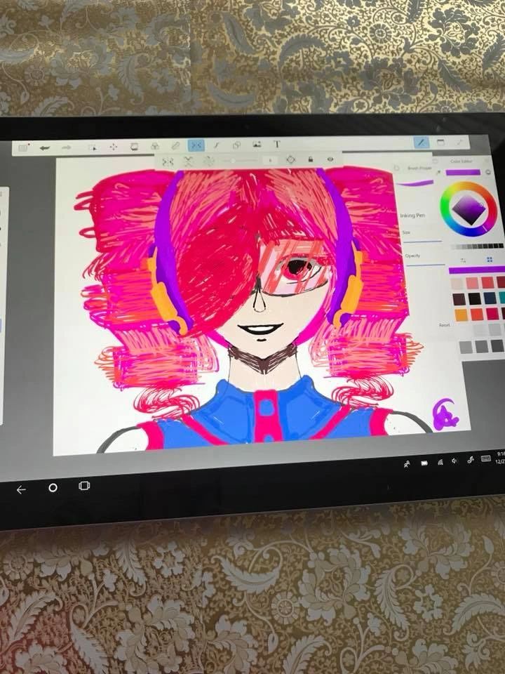 A digital drawing on a tablet screen showing a character with large pink and red hair, purple headphones and a blue and pink outfit.