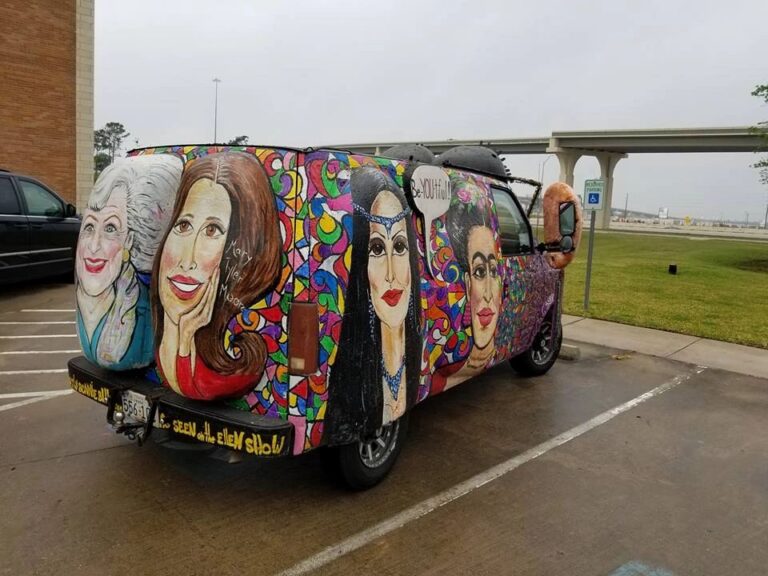 The back of the Women Rock Art Car, painted with portraits of women including a caricature holding her face, decorated with swirling colourful patterns underneath.