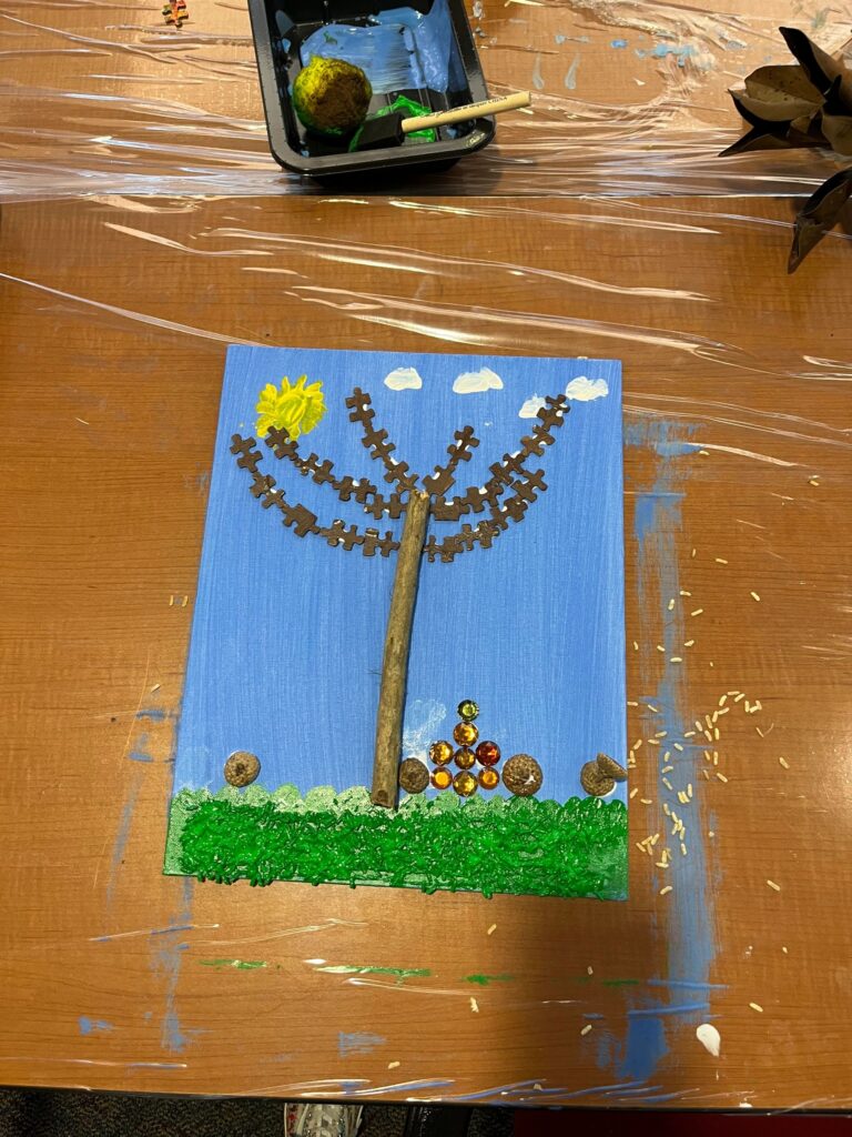 A fall tree canvas with a canopy of dark puzzle pieces catching the light, a twig trunk, amber gem clusters and green sprinkled grass below.
